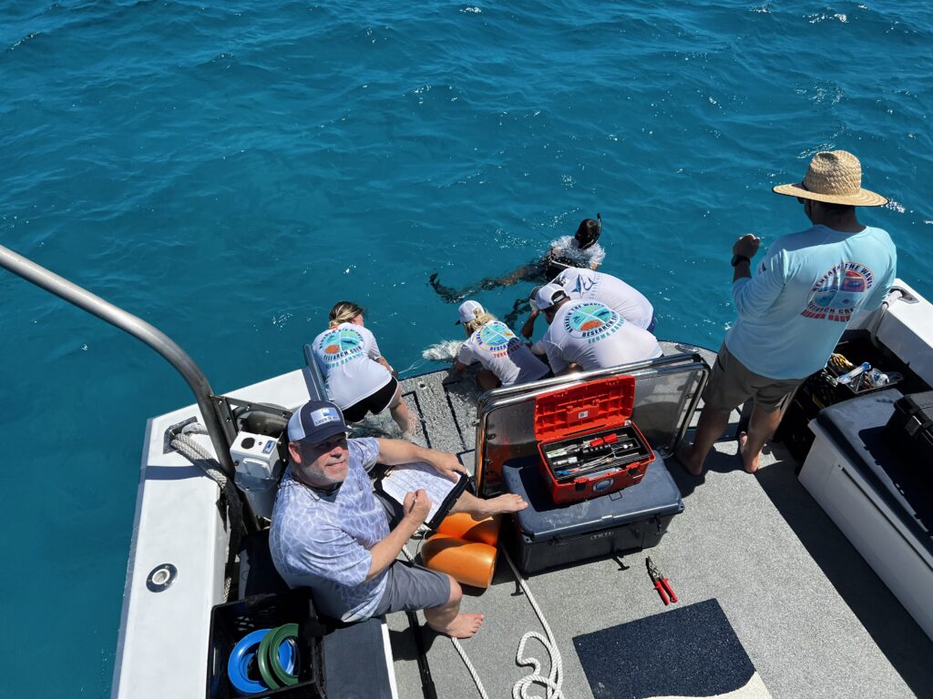 A team of researchers equipped with diving gear, preparing on a boat for deepwater exploration to investigate ocean ecosystems.