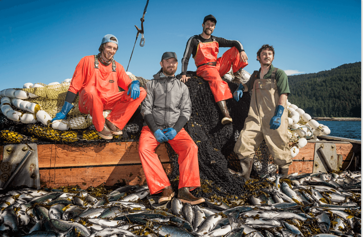 Fishermen on a boat surrounded by a large catch of fish, raising concerns about overfishing and the need for sustainable practices.