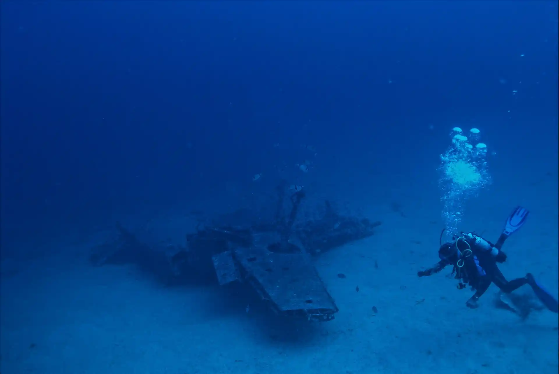 A diver exploring a large, dark shipwreck on the deep ocean floor, reminiscent of the discoveries made by submersibles like Alvin, prompting the question What is the Deep Ocean Research Submersible Alvin.